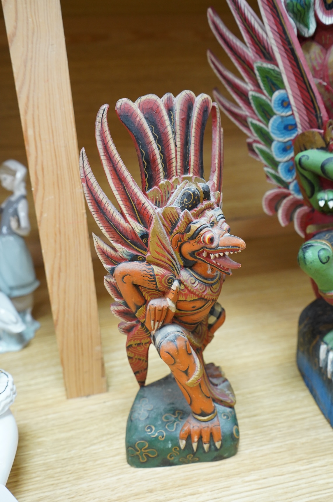 A Balinese painted and carved wood sculpture of Garuda, together with a smaller similar carving, largest 46cm high